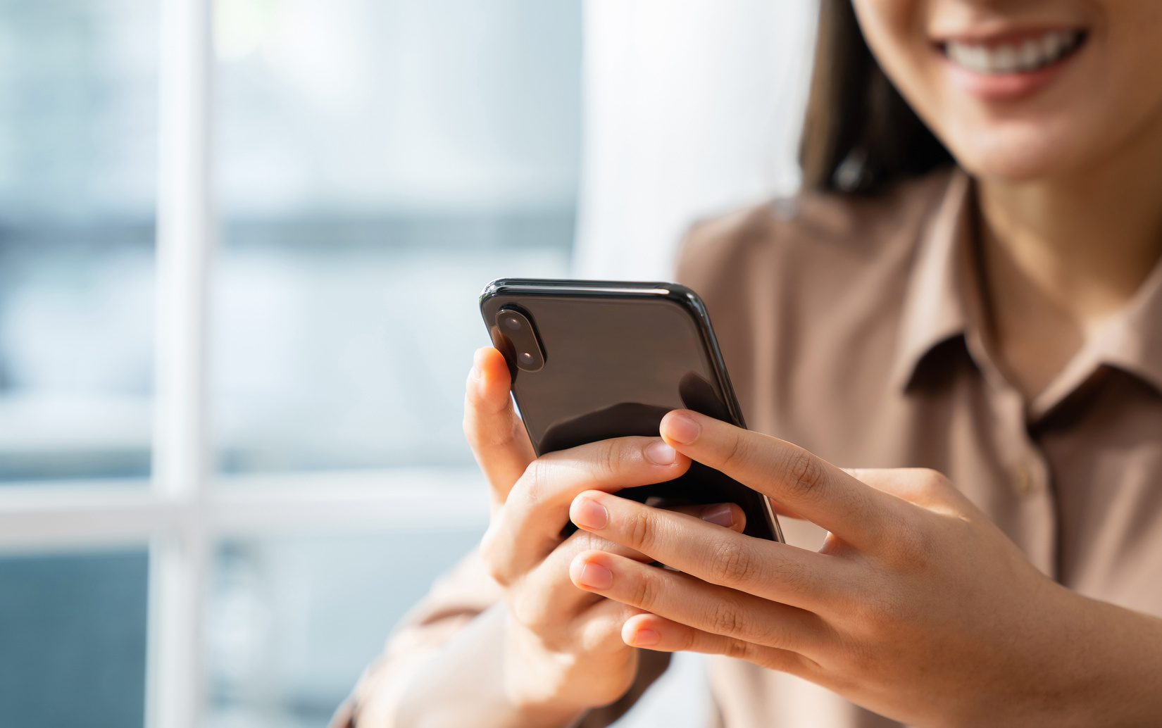 Smiling young woman hand holding smartphone with using social media on internet.